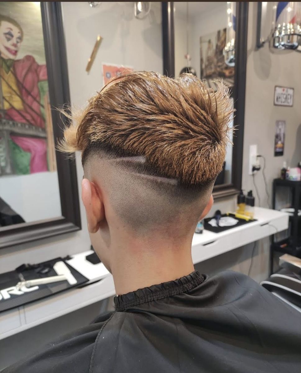 Blonde textured haircut with a fade and shaved line design